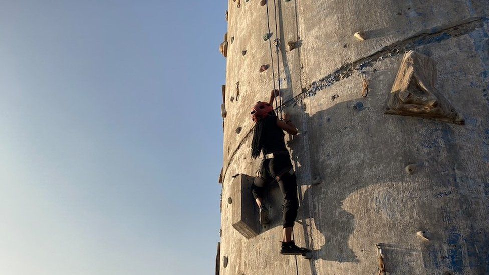 A person climbs up the climbing wall at the side of an old silo in Santiago