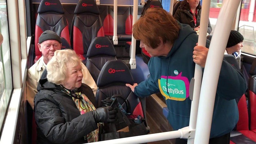 Chatty bus volunteer talking to passengers