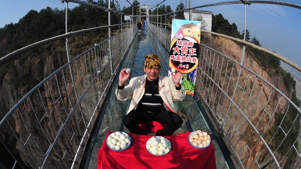 Pan Yizhong, a man known as the "King of Eaters", attempts an eating challenge on a glass-bottomed suspension bridge in Yueyang, Hunan Province Hunan province