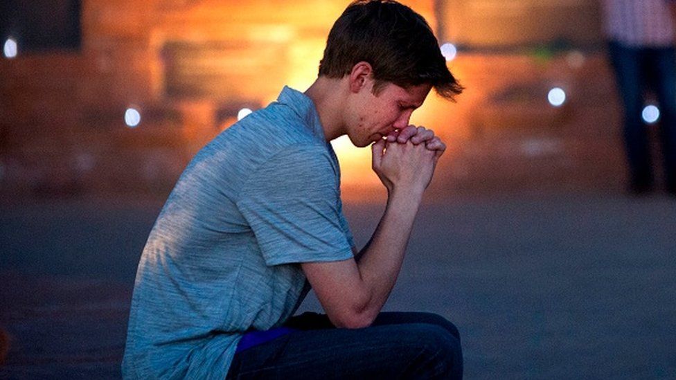 Spencer Greenlee, a student at Columbine High School, sits in prayer at the memorial