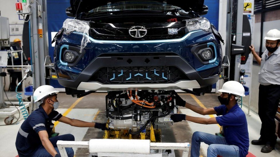 Рабочие устанавливают электродвигатель внутрь электромобиля Tata Nexon на заводе Tata Motors в Пуне, Индия.