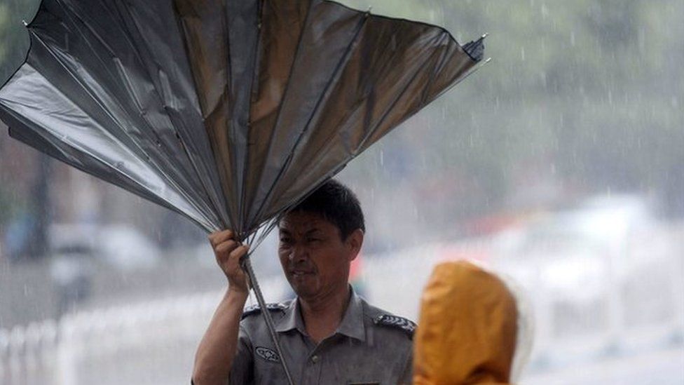 A man walks with an umbrella during heavy rain in Beijing on July 20, 2016