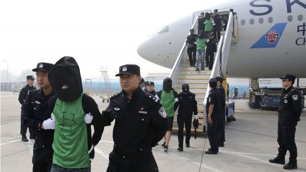 In this photo released by Xinhua News Agency, Chinese suspects involved in wire fraud are escorted off a plane upon arriving at the Beijing Capital International Airport in Beijing on Wednesday, April 13, 2016.