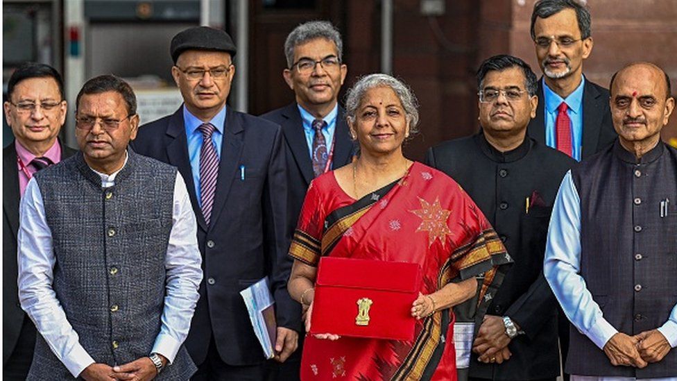 Министр финансов Индии Нирмала Ситхараман (в центре) позирует фотографу, покидая министерство финансов, чтобы представить годовой бюджет в парламенте в Нью-Дели, 1 февраля 2023 г.