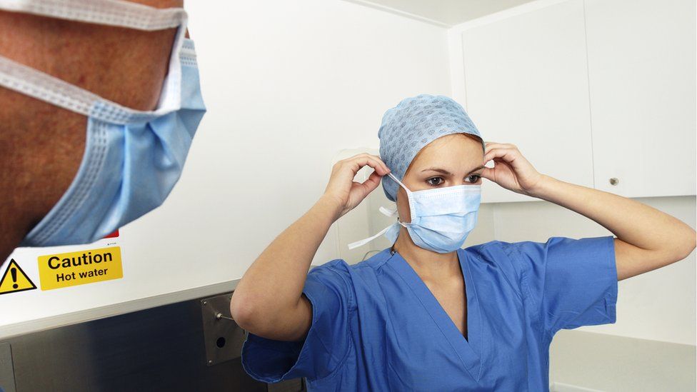 Generic image of a doctor adjusting her mask