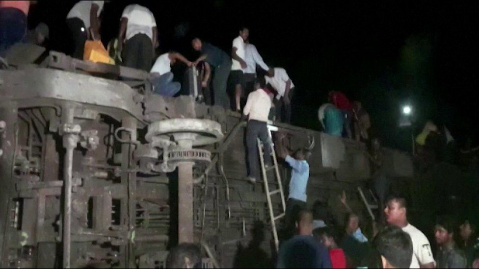 People in India climb over a derailed train