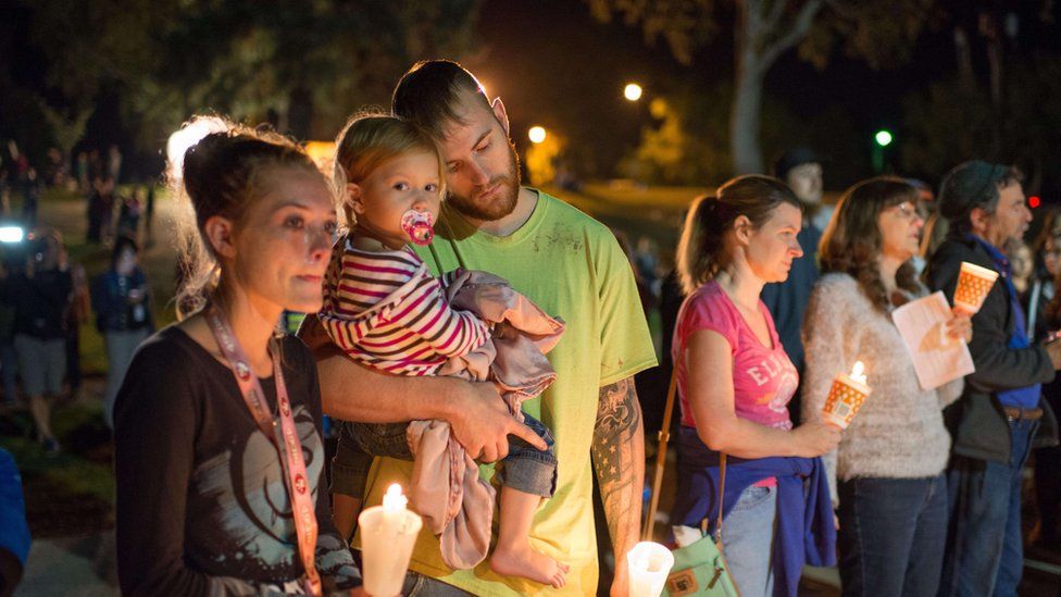 AJ Sewell (3rd L), 23, holds his daughter Alana (2nd L), 2, as they attend a candlelight vigil in Roseburg, Oregon late on October 1, 2015 for Oregon shooting