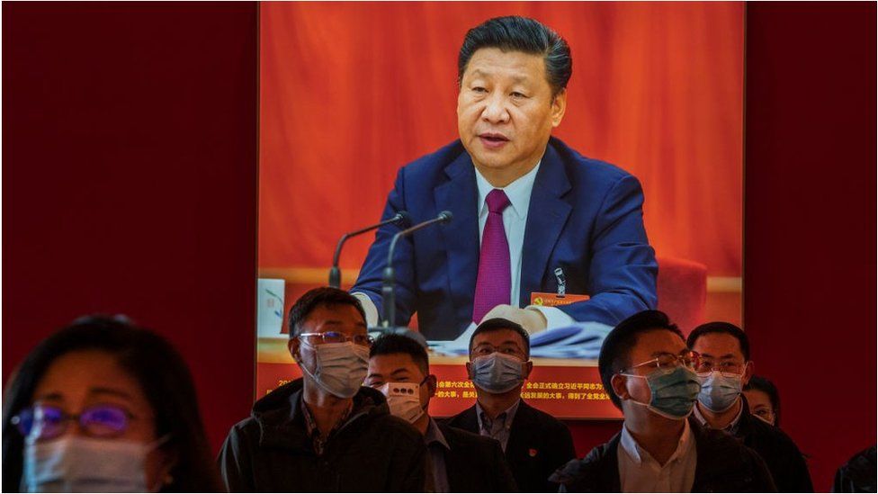Party members stand by an image showing Chinese President Xi Jinping as they listen to a guide at an exhibition highlighting Xi's years as leader, as part of the upcoming 20th Party Congress, on 12 October 2022 in Beijing, China.