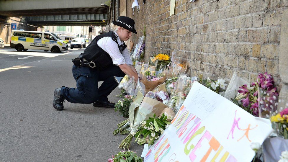 A police officer lays floral tributes at the scene of the attack
