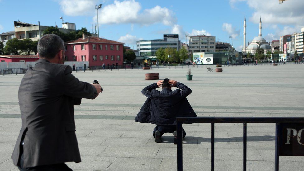 A plainclothes police officer orders the overpowered gunman to lay down just after an attack on Turkish journalist Can Dundar outside city"s main courthouse in Istanbul, Friday, May 6, 2016