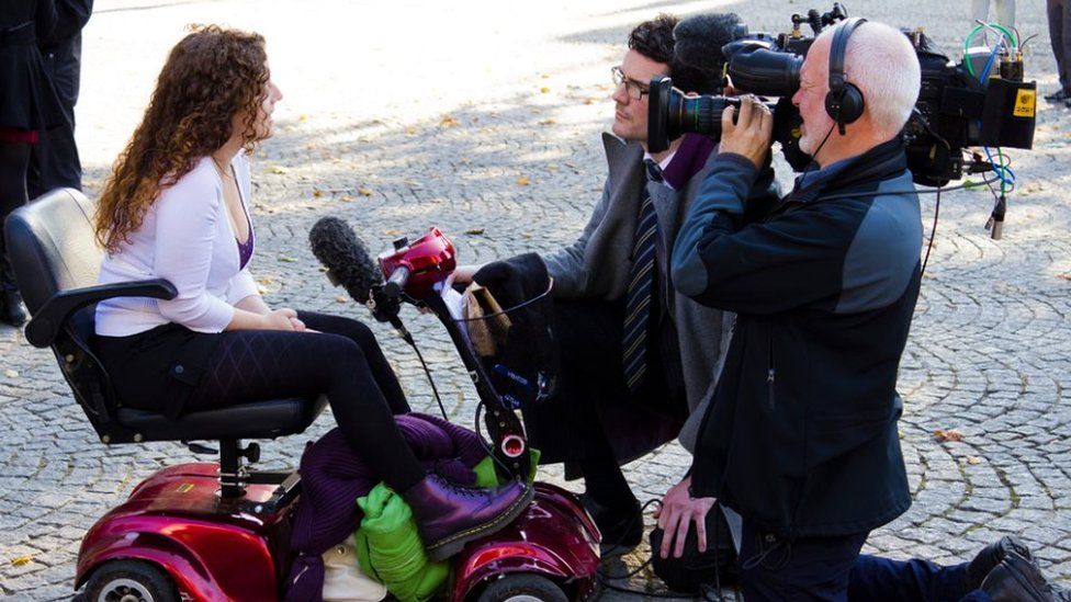 Kaliya Franklyn in her electric scooter talking to a TV crew