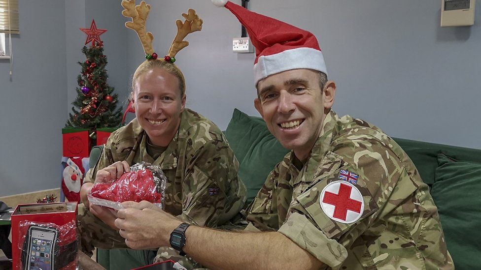 Two members of the armed forces wearing Christmas-themed headwear