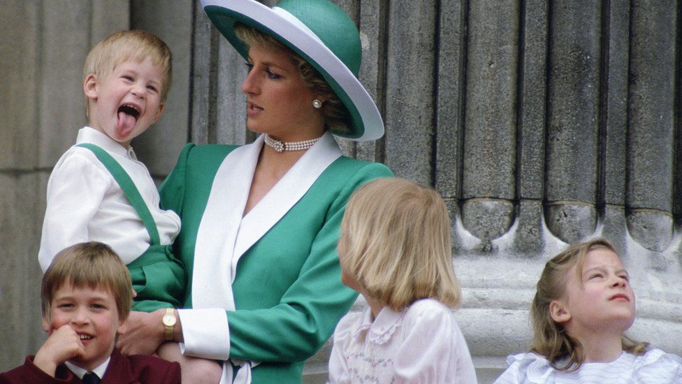 Young Prince Harry sticking his tongue out in the balcony, while being held by his mother Princess Diana