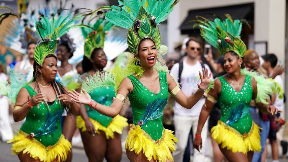 Performers at the Notting Hill Carnival in London dressed in green and yellow outfits
