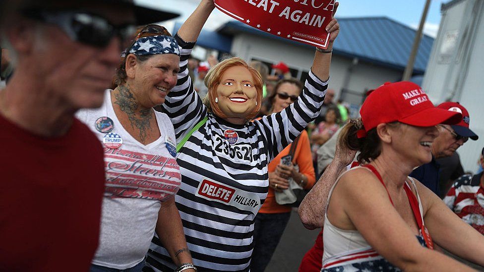 a person wearing a hillary mask at a rally in 2016