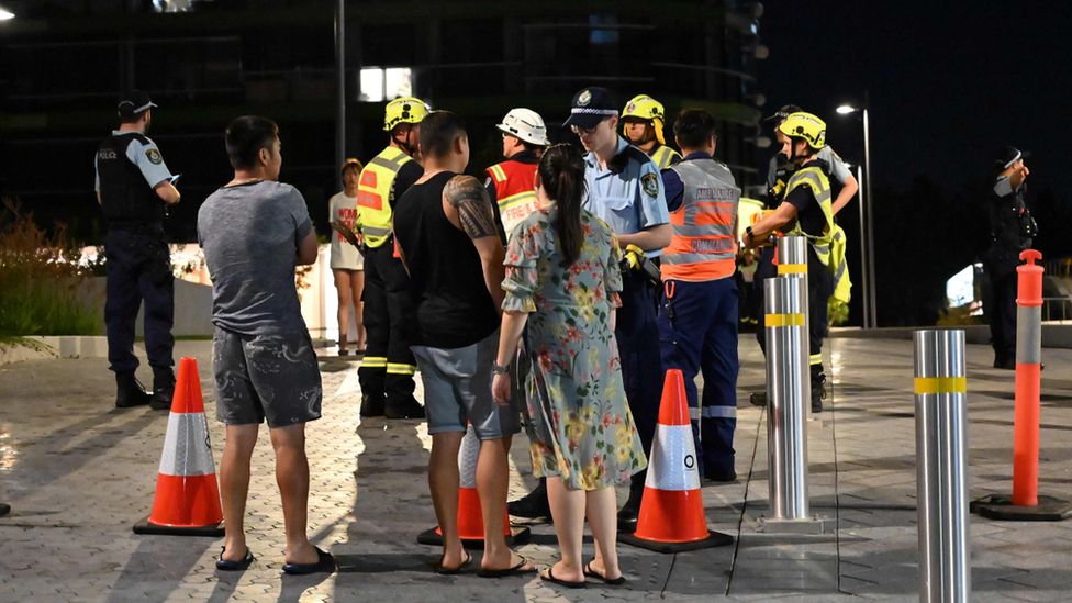 Police talk with evacuated residents from the Opal Tower on Monday