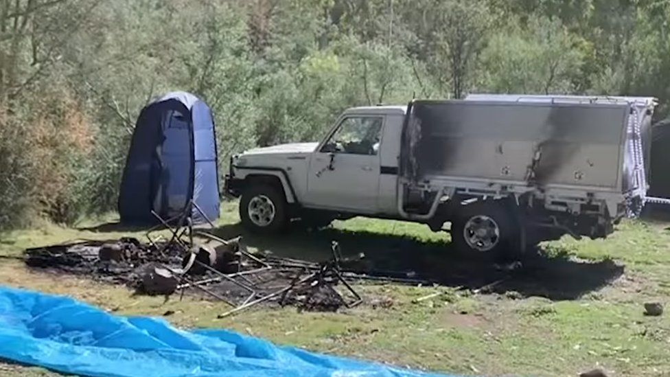 A burnt-out campsite seen next to a car with signs of fire damage