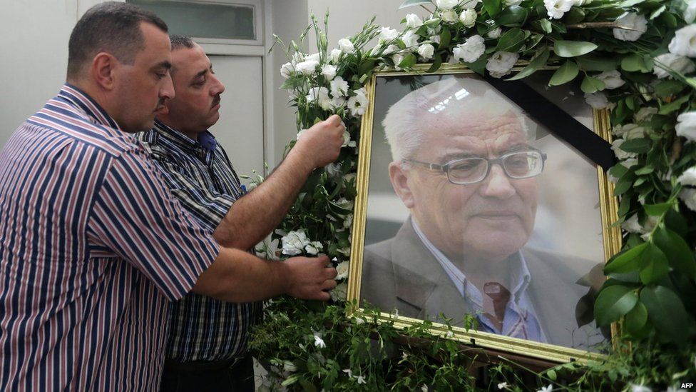 Khaled al-Asaad's sons with a portrait of him during a ceremony in his memory at Syria's National Museum in Damascus (23 August 2015)