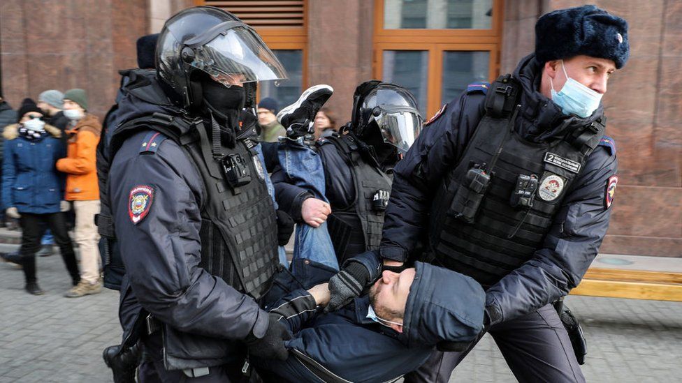 Troops in uniform carrying a protestor