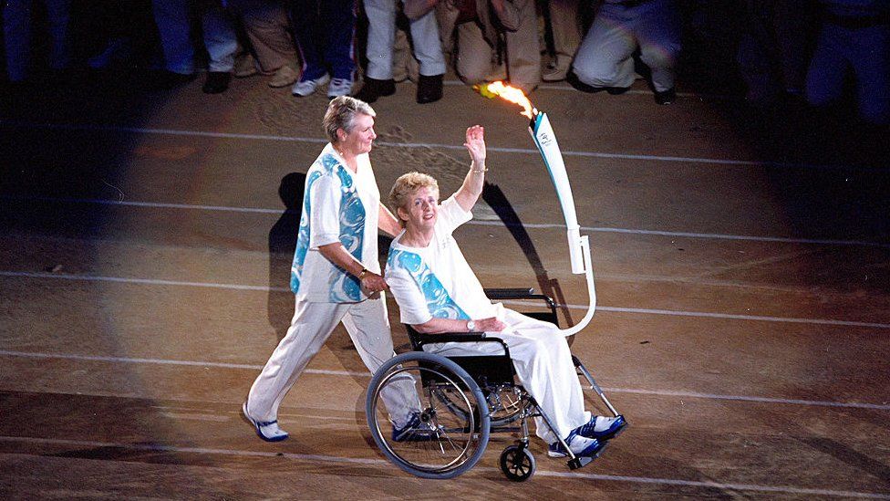 Betty Cuthbert is pushed by Raelene Boyle during the Opening ceremony of