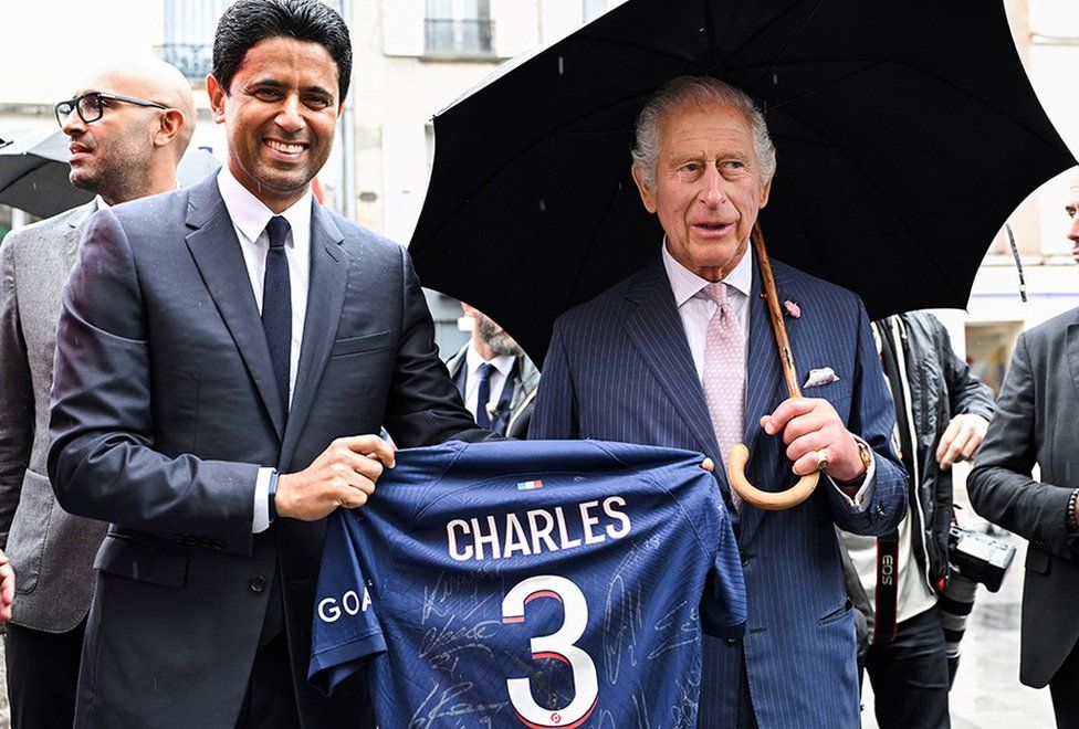 Paris Saint Germain's president Nasser al-Khelaifi offers King Charles a club jersey during the visit to Saint-Denis
