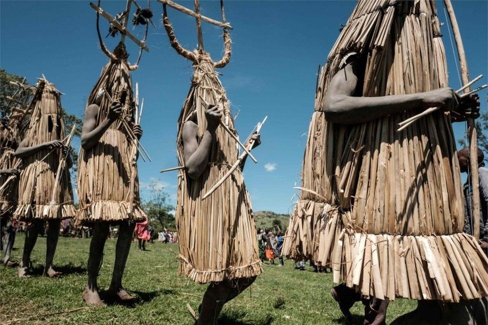 Circumcised Maasai young men wearing a ritual costume covered with hunted birds, come out from the bush to receive blessing from ceremony masters near Kilgoris, Kenya