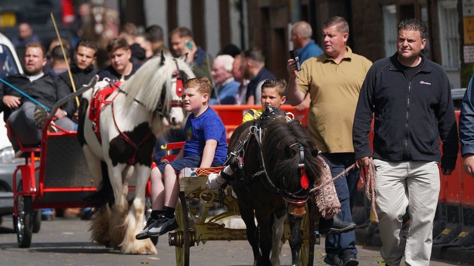 Crowds lead horse and traps through town
