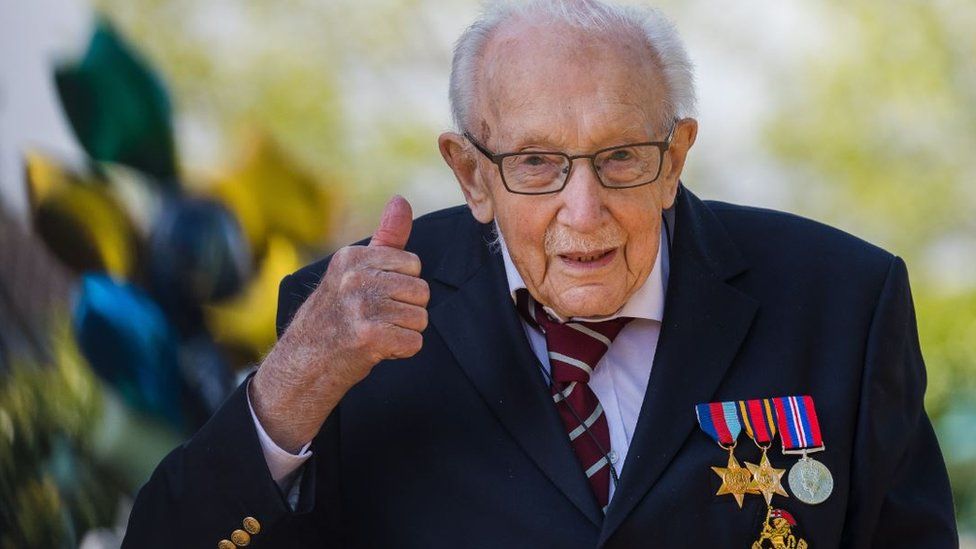 Capt Tom Moore walking in his suit, giving a thumbs up