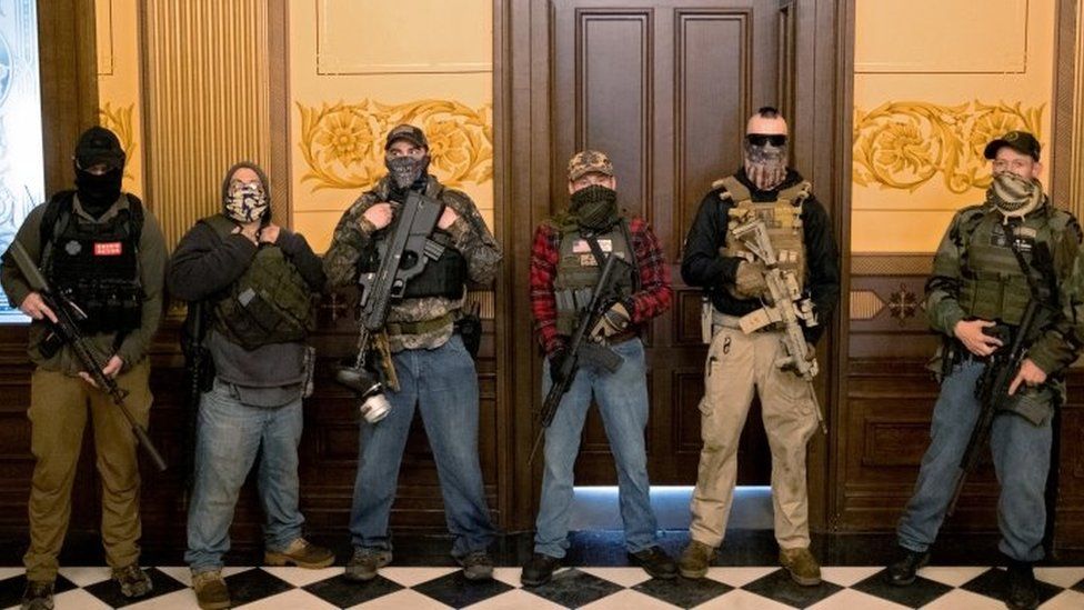 A militia group with no political affiliation from Michigan, including Joseph Morrison (3rd R), Paul Bellar (2nd R) and Pete Musico (R) stand in front of the governor's office after protesters occupied the state capitol building during a vote to approve the extension of Whitmer's emergency declaration/stay-at-home order due to Covid-19 outbreak, in Lansing, Michigan, April 30, 2020