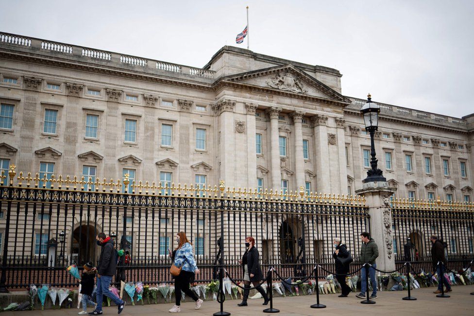 Well-wishers pay their respects as floral tributes to Britain's Prince Philip, Duke of Edinburgh are laid outside Buckingham Palace, central London on April 10, 2021