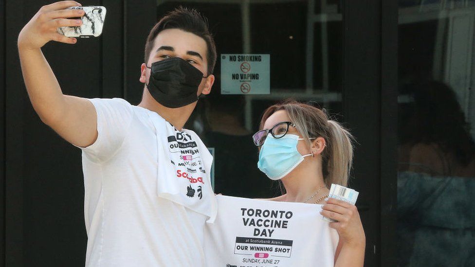 A vaccinated couple take a selfie as thousands line up and are jabbed at the Scotiabank Arena in Toronto for a vaccine drive in June