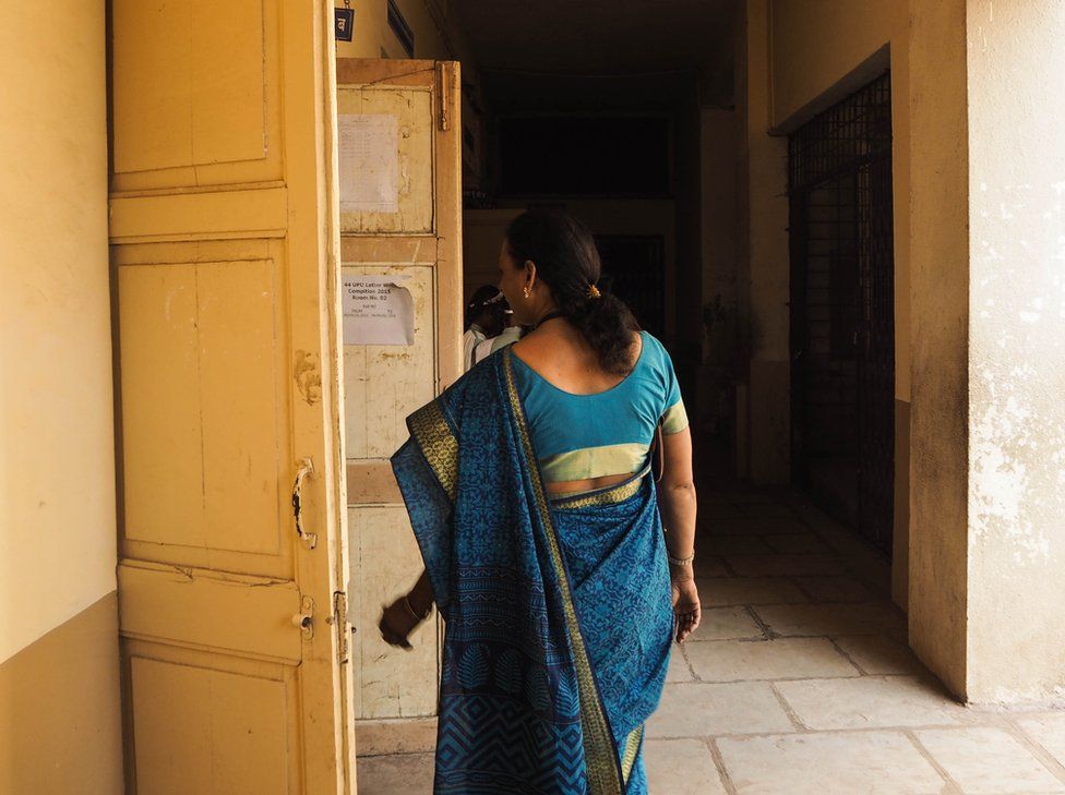 India, 2015. A woman in a sari walks along a passage.