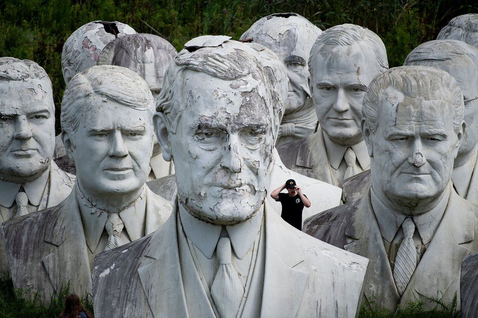 A man stands behind a giant bust of US President Woodrow Wilson