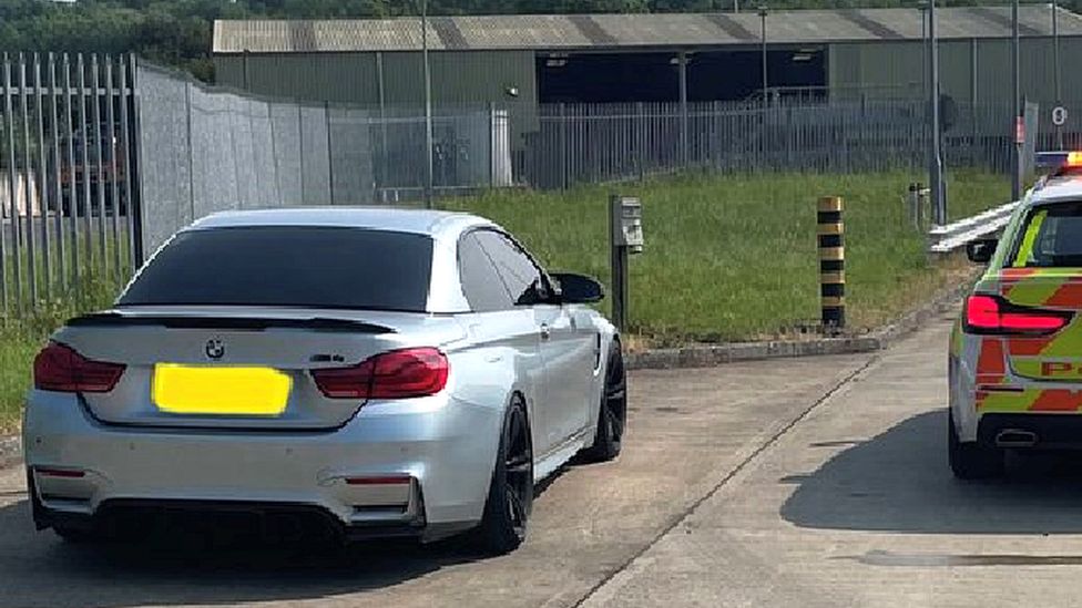 A metallic  BMW adjacent  to a constabulary  car   successful  a layby