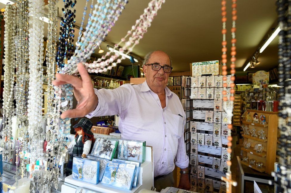 Shopkeeper Bernie Byrne, 74, pushes aside the rosaries he sells in his shop