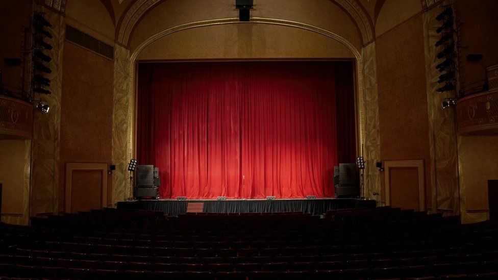 A view of a red curtain on the stage of an empty theatre