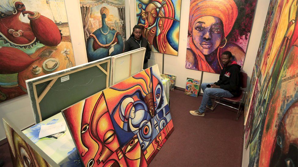 People are seen at a stall at the Kenya Art Fair 2015 exhibition