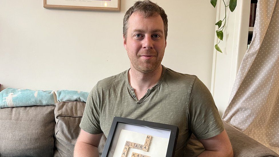 A man holding a picture of names of his family