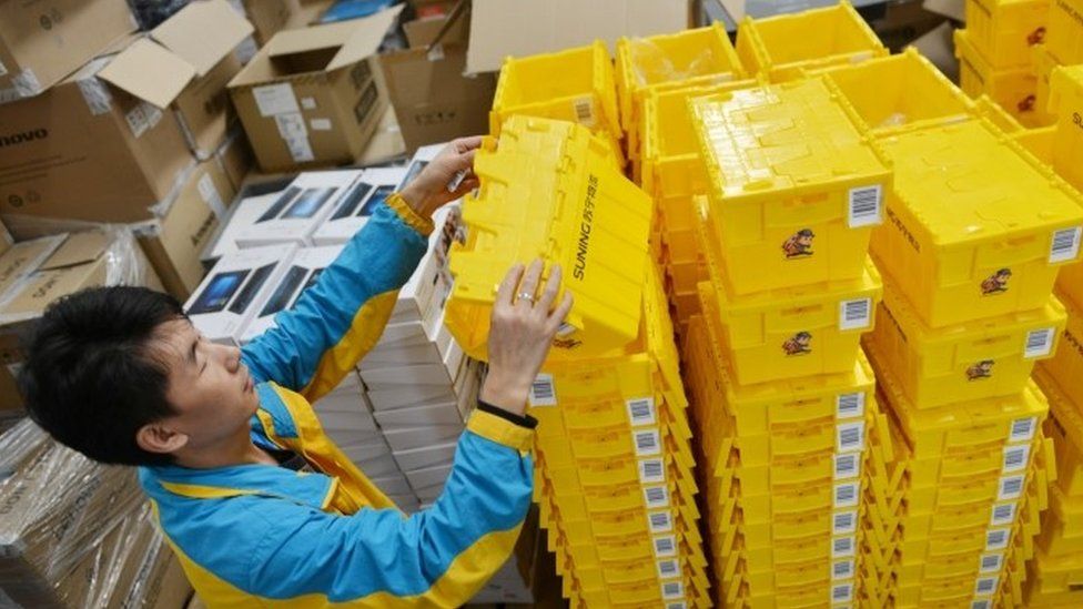 An employee piles up reusable boxes to be used ahead lof the Singles Day online shopping festival in Nanjing, Jiangsu province, China (28 October 2017)