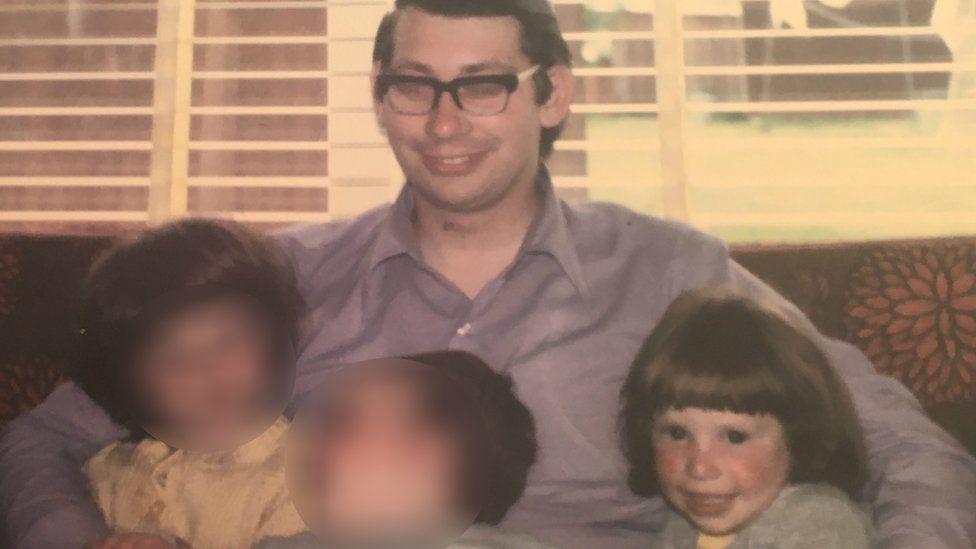 Richard Haynes sits on a couch with his three children including Jeni on the right