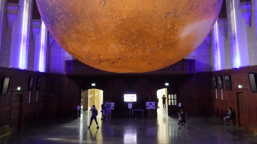 Half of Mars planet with people walking underneath