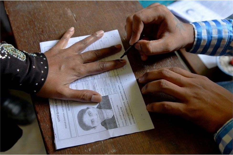 An Indian election official (R) puts indeliable ink on the finger of a voter before she casts her ballot in the Karnataka Legislative Assembly Elections at a polling station in Bangalore on May 12, 2018.