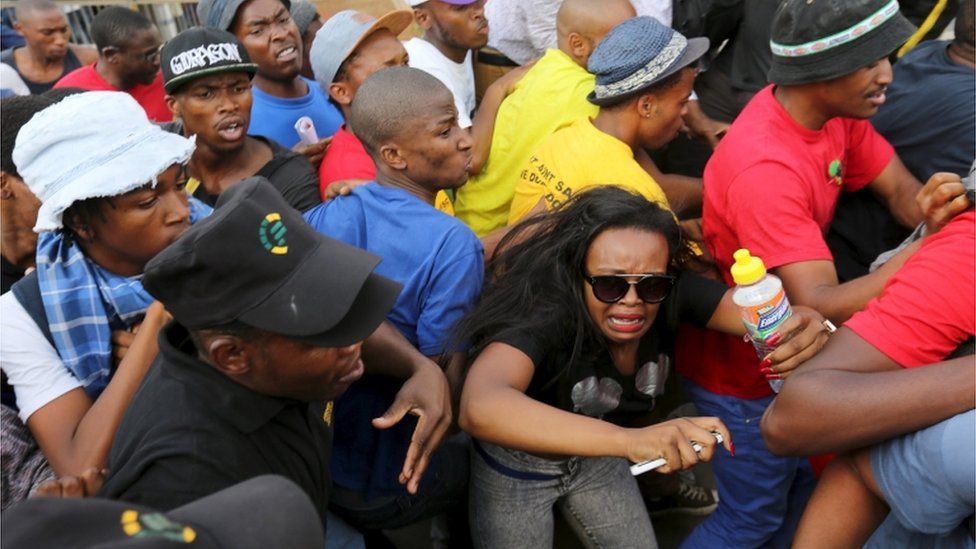 Student reacts during their confrontation with security guards as they protest over planned increases in tuition fees outside the University of Johannesburg