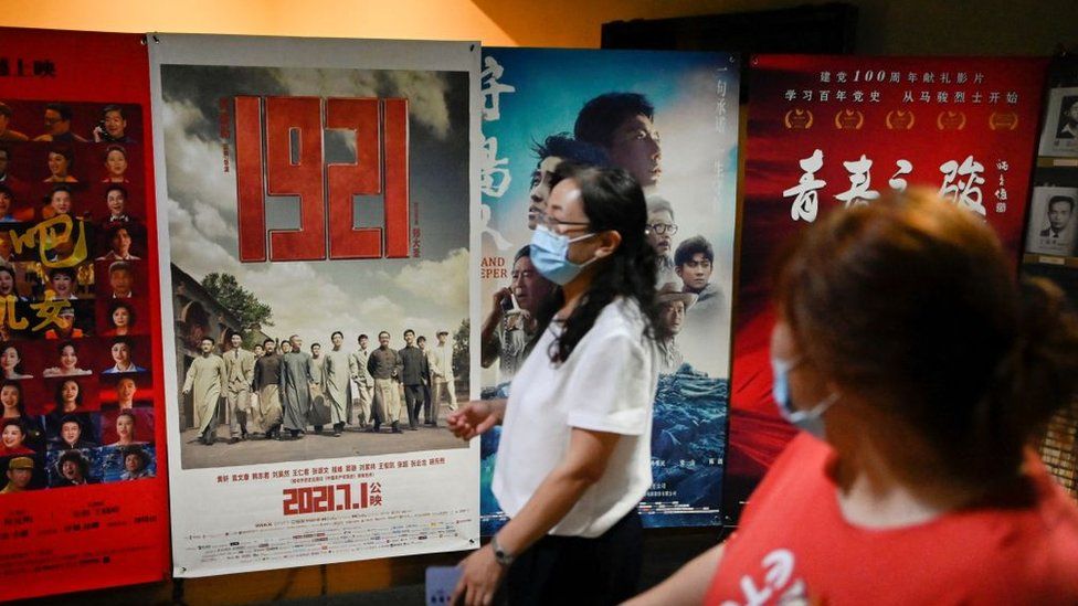 People walk past a poster for '1921', a film about the founding of the Communist Party of China in the same year, ahead of the Chinese Communist Party's 100th founding anniversary at a cinema in Beijing.