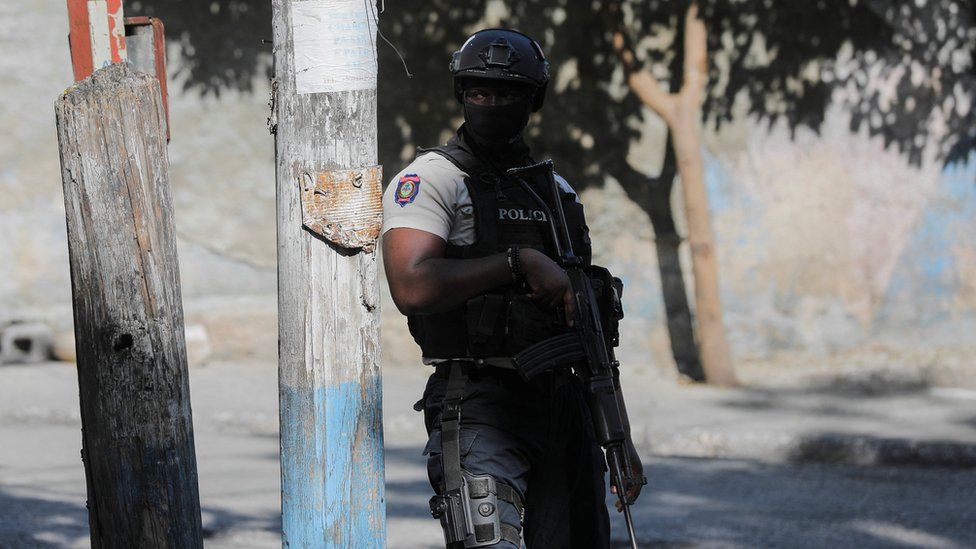 A police officer stands guard near a site where alleged gang members were set on fire by a crowd of people in Port-au-Prince