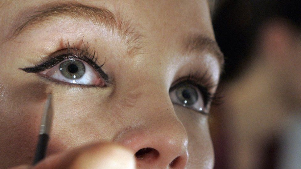 A woman putting on eyeliner