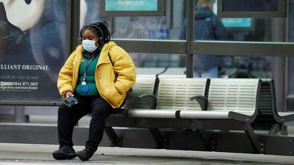 A woman wearing a face mask waits for a tram in Manchester, following the outbreak of the coronavirus disease (COVID-19), Manchester, Britain