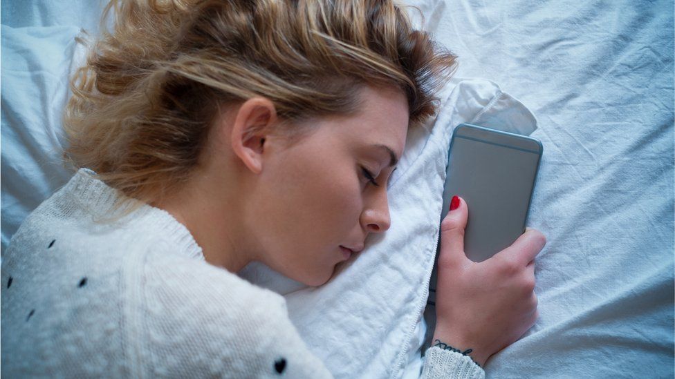 Young person asleep and holding a phone