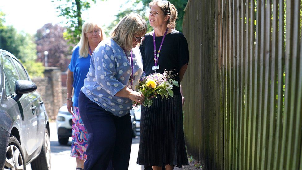 Staff from a local hospice lay flowers on Magdala Road, Nottingham, after three people were killed and another three hurt in connected attacks on Tuesday morning