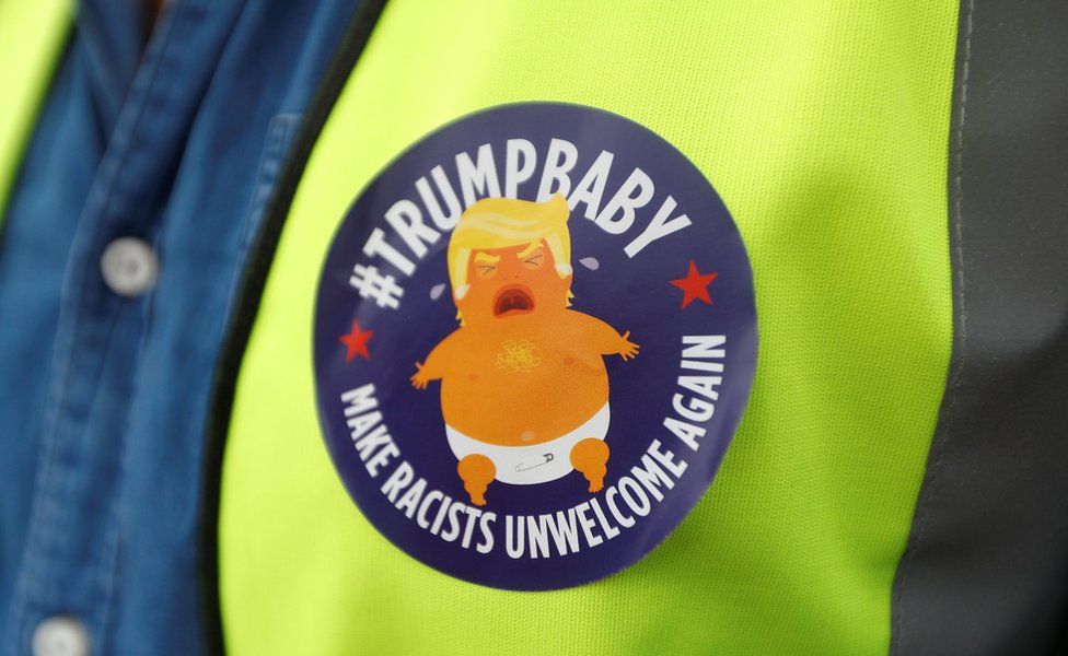 A demonstrator wears a badge depicting US President Donald Trump as a baby